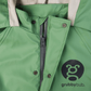 Close up image of a sage green waterproof rain suit showing zip, neck closure and hood